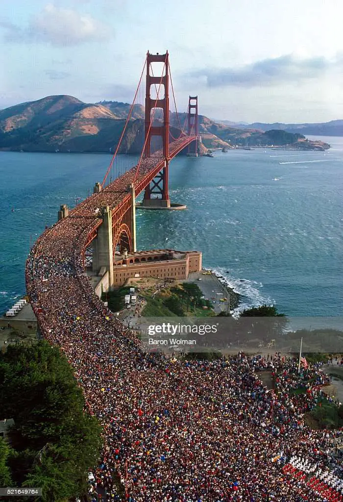 A crowd of people walk across the Golden Gate Bridge for ...